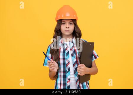 serious kid in construction helmet hold in clipboard and pen, education Stock Photo