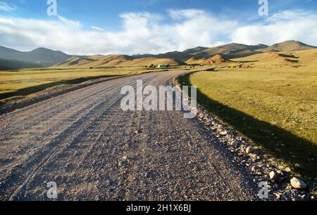 Unpaved road and yurts near Son-Kul lake and Tian Shan mountains in Kyrgyzstan Stock Photo