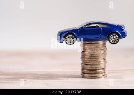 Car on stack of coins. Car loan, Finance, saving money, insurance and leasing time concepts. Stock Photo
