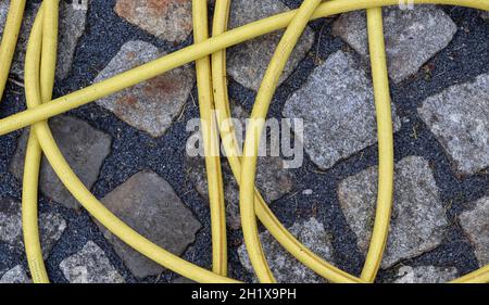 Top view of hosepipe on grass and cobblestone surfaces. Minimalistic conception. Stock Photo