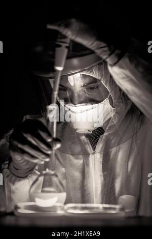 Life scientist researching in bio hazard laboratory. Focused life science professional working on experiment in high protection degree work laboratory Stock Photo