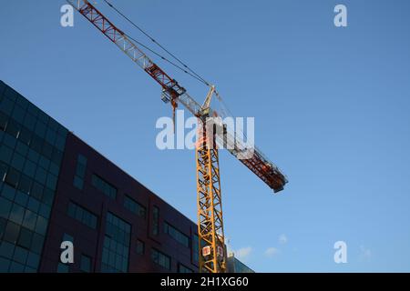 Tower crane working at construction site on blue sky background with white clouds. Construction process of the new residential buildings Stock Photo