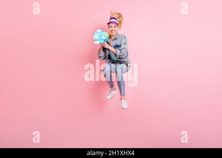 Full body photo of cute sporty lady shoot jump wear jeans shirt cap isolated on pink background Stock Photo