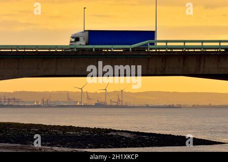 Lorries travelling on the M4 Second Severn Crossing, now called the Prince of Wales Bridge, from Aust side in England, UK. With Sunset. Stock Photo