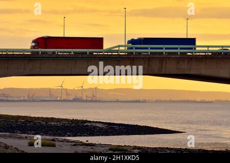 Lorries travelling on the M4 Second Severn Crossing, now called the Prince of Wales Bridge, from Aust side in England, UK. With Sunset. Stock Photo