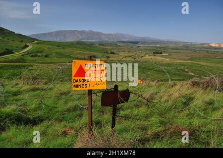 Minefield danger mines yellow warning sign on a barbed wire fence in the Golan Heights, Israel Stock Photo