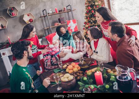 Photo portrait santa claus giving xmas presents to little kids sitting at table with full family in decorated apartment Stock Photo
