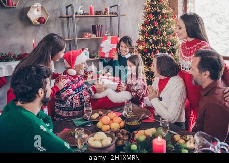 Photo portrait small children receive present box on christmas from santa claus sitting at table with full family Stock Photo