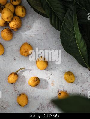 Loquats and loquat leafs on stone table Stock Photo