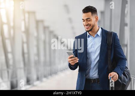 Handsome Young Arab Businessman Using Smartphone While Standing At Airport Terminal Stock Photo