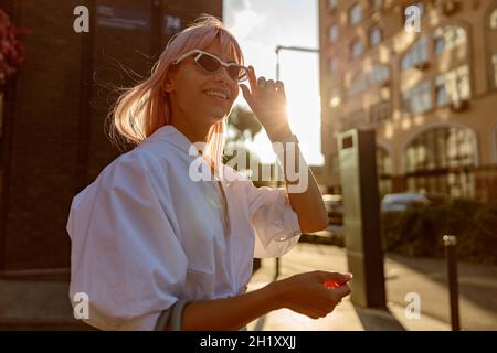 Joyful young woman in sunglasses standing on the street Stock Photo