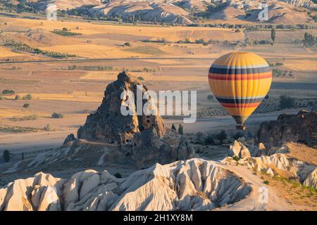 landscape with lonely hot air balloon with rainbow colors pattern rising over the Cappadocian valley panorama in the morning light with chimney rock h Stock Photo