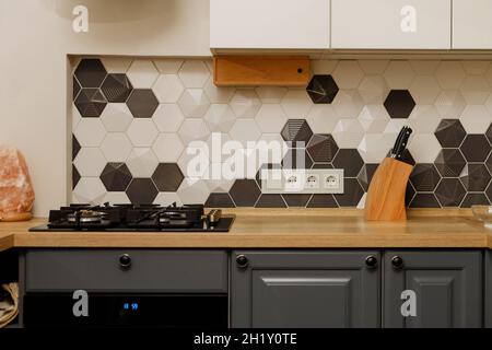 Modern kitchen interior with hood with white and gray cabinets, mixed style. oven, hob, tiles, cabinet, wooden countertop Stock Photo