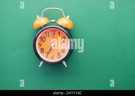 orange old alarm clock on green background  Stock Photo