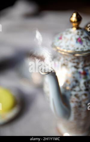 Traditional antique tea pot English culture afternoon tea with hot tea and smoke on diner table, vintage high tea concept elegant stylish set Stock Photo