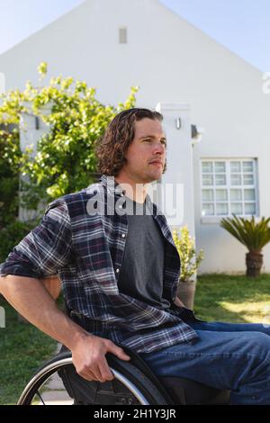 Caucasian disabled young man sitting on wheelchair smiling in the garden Stock Photo