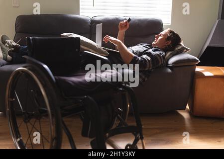 Caucasian disabled man using laptop while lying on the couch at home Stock Photo