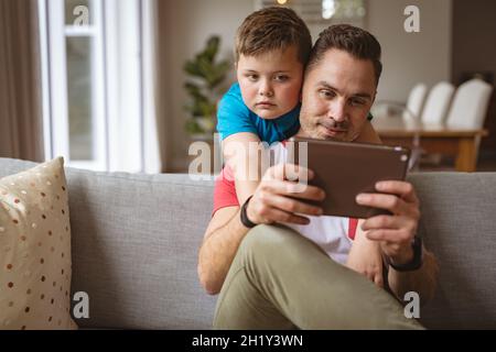 Caucasian father and son using digital tablet on the couch at home Stock Photo