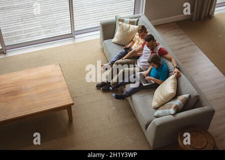 Overhead view of caucasian father and two sons using laptop and digital tablet at home Stock Photo