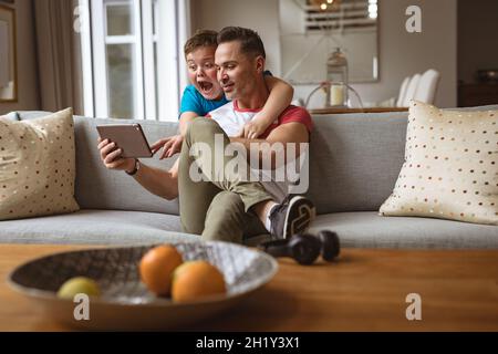 Caucasian father and son using digital tablet on the couch at home Stock Photo