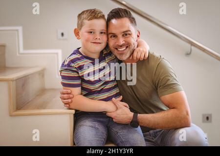 Portrait of caucasian father and son smiling sitting on the stairs at home Stock Photo