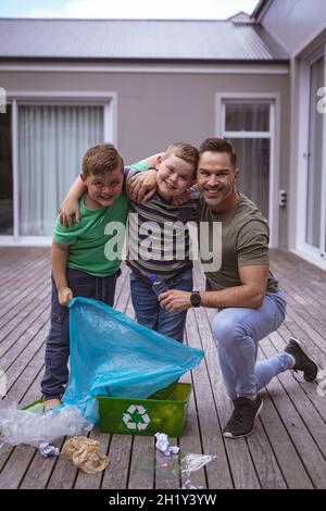 Portrait of caucasian father and two sons collecting plastic materials in a bag outdoors Stock Photo