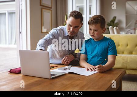 Caucasian father using laptop to help his son with homework at home Stock Photo