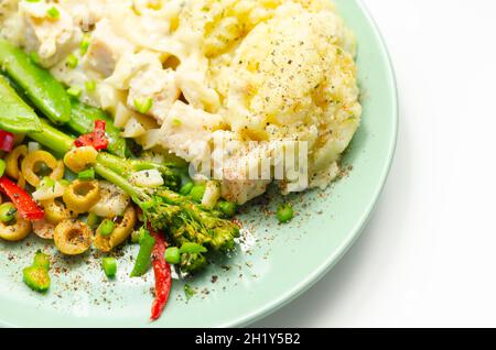 Tender pieces of smoked haddock and pollock in a creamy cheese sauce sat beneath buttery mash served with vegetables, classic English meal Stock Photo