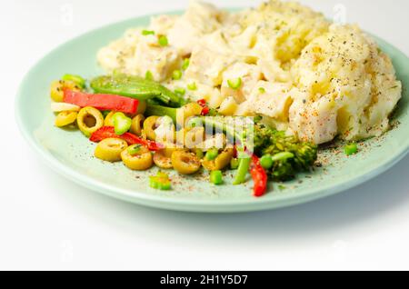 Tender pieces of smoked haddock and pollock in a creamy cheese sauce sat beneath buttery mash served with vegetables, classic English meal Stock Photo