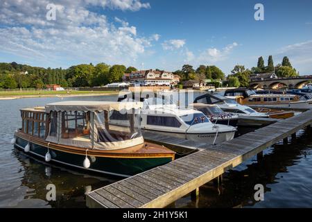 Boats moored on the River Thames at Henley on Thames in Oxfordshire. On the opposite (Remenham) bank is the building of the famous Leander Rowing Club Stock Photo