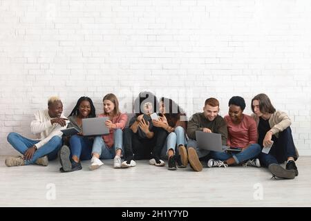 Joyful multiracial friends having fun, using gadgets and chatting Stock Photo