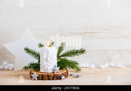 Vintage Nordic style minimalist Christmas background with a lot of copy space. Selective focus on snow ball pattern white candle burning, star shape. Stock Photo