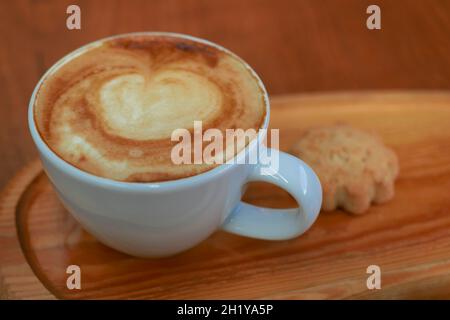 Directly above shot of cup of cappuccino and cookie on wooden background Stock Photo