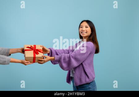 Presents delivery, birthday and new year holiday celebration concept. Happy asian lady receiving wrapped gift box Stock Photo