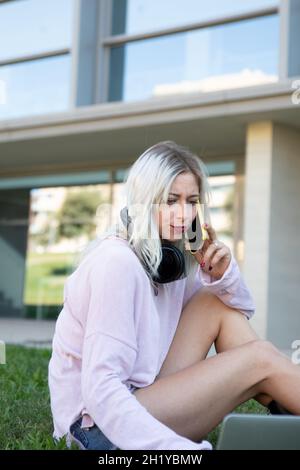 A young beautiful student woman using a smartphone and laptop at the university Stock Photo