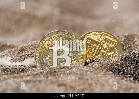 Two coins of the digital currency Bitcoin in the sand Stock Photo