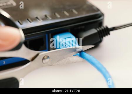 Scissors cutting LAN cable - no more internet. Stock Photo