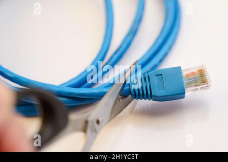 Scissors cutting LAN cable - no more internet. Stock Photo