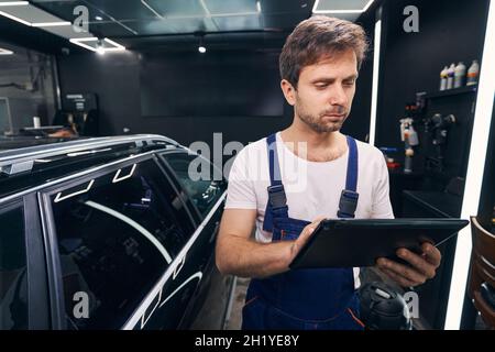 Auto repairman is checking information on tablet Stock Photo