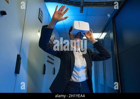 Happy young woman using virtual reality headset indoors Stock Photo