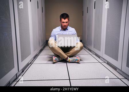 Sysadmin working on laptop in data center Stock Photo