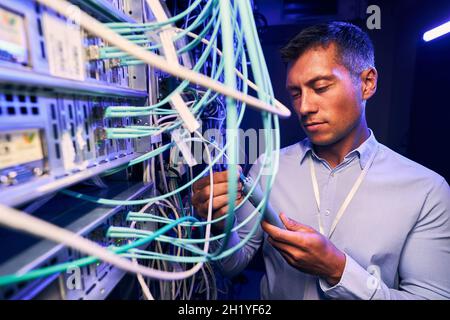 Serious focused IT technician testing cabling performance Stock Photo