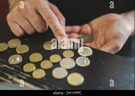 business man counting money. rich male hands holds and count coins of different euros on table in front of a laptop Stock Photo