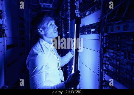Employee using additional lighting for checking hardware equipment Stock Photo