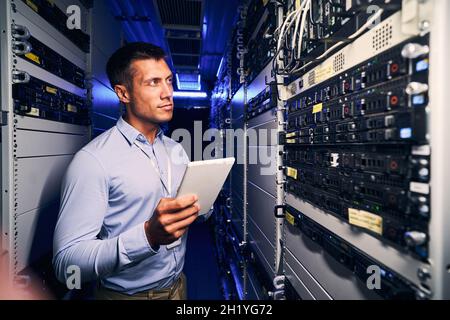Concentrated tranquil system administrator inspecting networking equipment Stock Photo