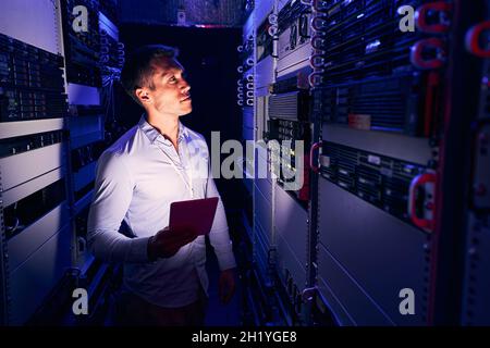 Data center employee inspecting equipment in server room Stock Photo