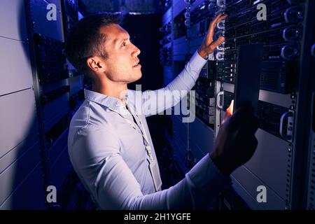 System administrator inspecting storage hardware in server room Stock Photo