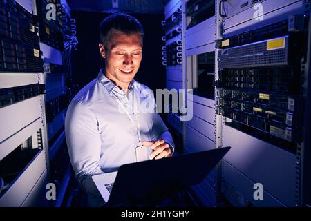 Sysadmin working on notebook computer in server room Stock Photo