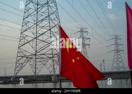 Chinese flag waving in front of high-voltage transmission towers in Tianjin, China. 19-Oct-2021 Stock Photo