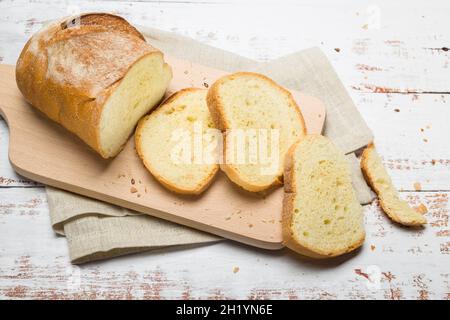 Sliced fresh bread and crumbs on wooden cutting board. Top view Stock Photo